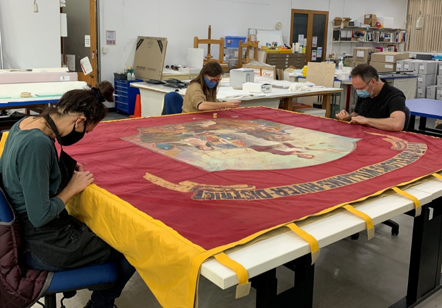 Photo: Members of the International Conservation Services team performing conservation work on the banner.
